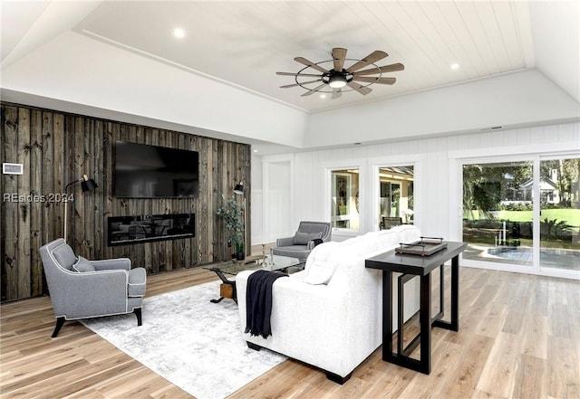 living room featuring crown molding, light hardwood / wood-style flooring, ceiling fan, a fireplace, and wood walls