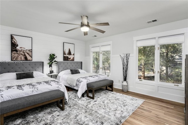 bedroom with multiple windows, hardwood / wood-style flooring, access to outside, and ceiling fan