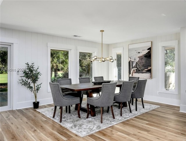 dining space with a notable chandelier, wood-type flooring, and a wealth of natural light