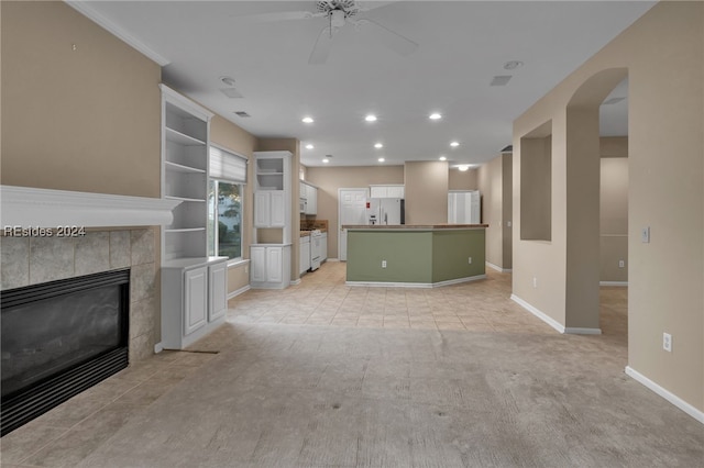 unfurnished living room with ceiling fan, light carpet, built in features, and a fireplace