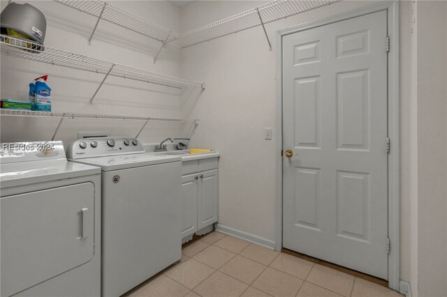 laundry area featuring cabinets, separate washer and dryer, sink, and light tile patterned floors