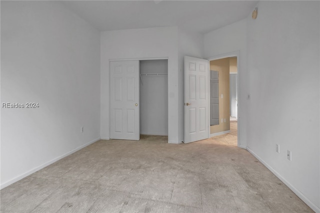 unfurnished bedroom with light colored carpet and a closet