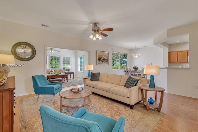 living room with ceiling fan with notable chandelier and light hardwood / wood-style floors