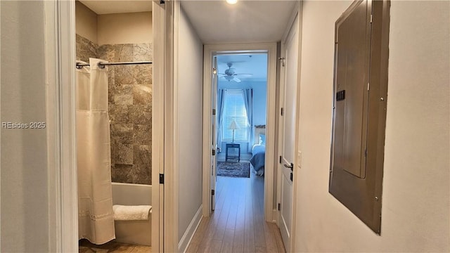 corridor with hardwood / wood-style floors and electric panel