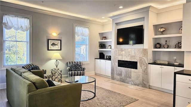 living room with a healthy amount of sunlight, a tile fireplace, and light hardwood / wood-style flooring