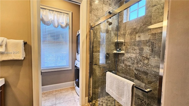 bathroom featuring a shower with door, vanity, plenty of natural light, and stacked washer and dryer