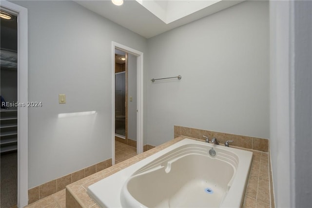 bathroom featuring shower with separate bathtub and a skylight