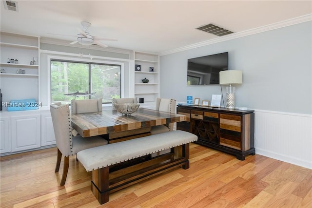 dining room with built in shelves, light hardwood / wood-style flooring, ornamental molding, and ceiling fan