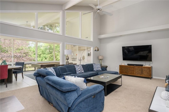 carpeted living room with beam ceiling, plenty of natural light, ceiling fan, and a high ceiling