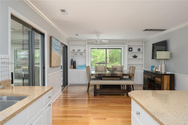 kitchen with built in features, white cabinets, crown molding, and light hardwood / wood-style flooring