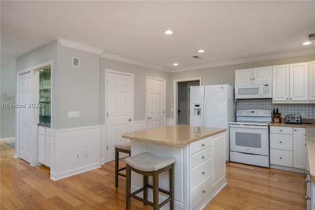 kitchen with white cabinetry, a center island, crown molding, white appliances, and light hardwood / wood-style flooring