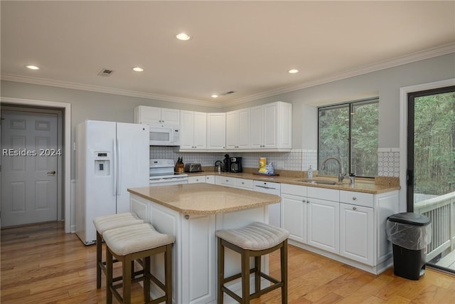 kitchen featuring sink, white appliances, a center island, and white cabinets