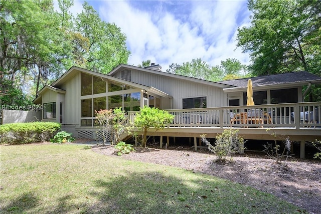 back of house featuring a wooden deck, a yard, and a sunroom