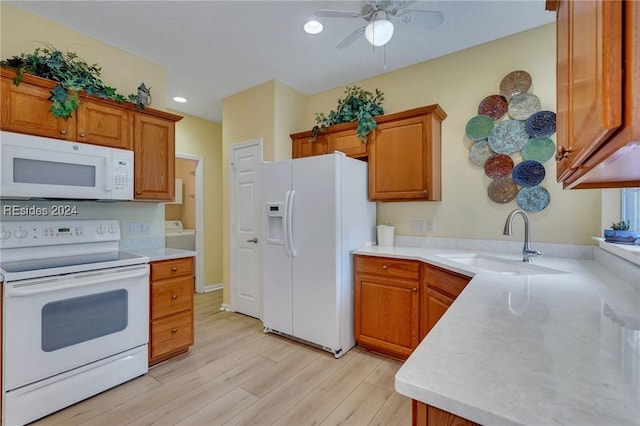 kitchen with washer / dryer, sink, white appliances, light hardwood / wood-style flooring, and ceiling fan