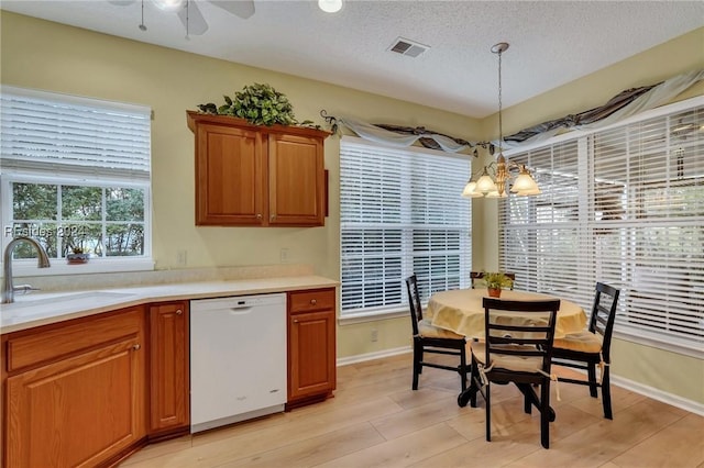 kitchen with pendant lighting, sink, dishwasher, a textured ceiling, and light wood-type flooring