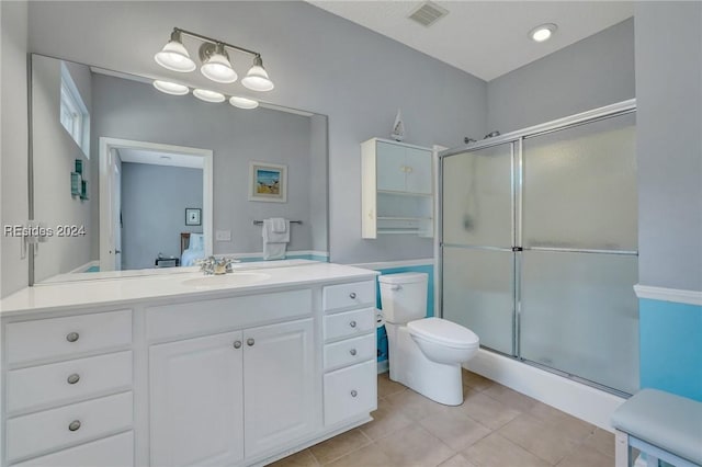 bathroom featuring tile patterned flooring, vanity, toilet, and a shower with shower door