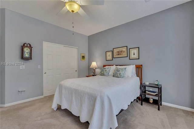 bedroom with light colored carpet, a textured ceiling, ceiling fan, and a closet