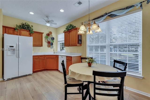 kitchen featuring sink, white appliances, hanging light fixtures, light hardwood / wood-style floors, and ceiling fan with notable chandelier