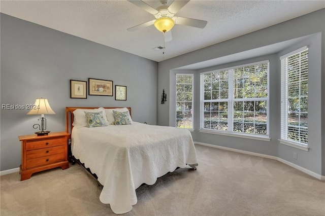 carpeted bedroom featuring multiple windows, a textured ceiling, and ceiling fan