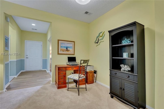 carpeted office space featuring a textured ceiling