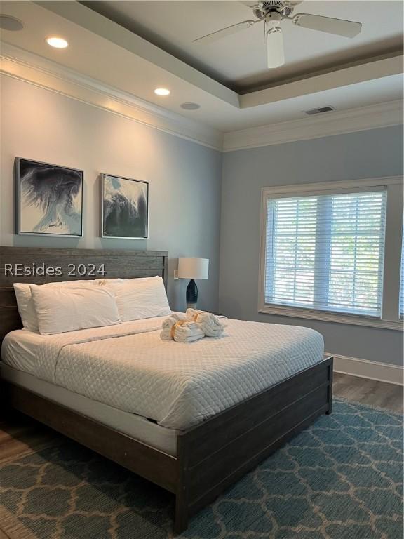 bedroom featuring a tray ceiling, dark hardwood / wood-style floors, and ceiling fan