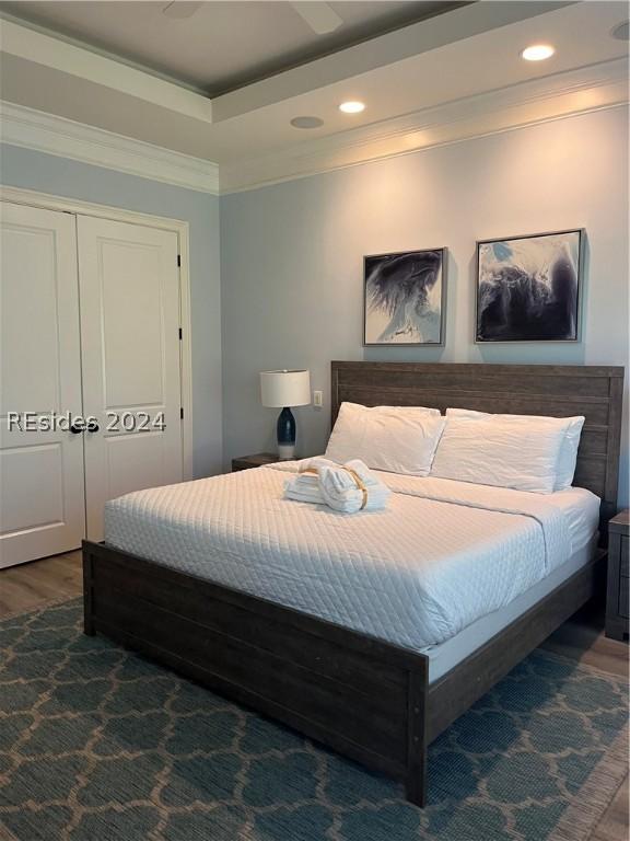 bedroom featuring ceiling fan, a tray ceiling, dark hardwood / wood-style flooring, and a closet