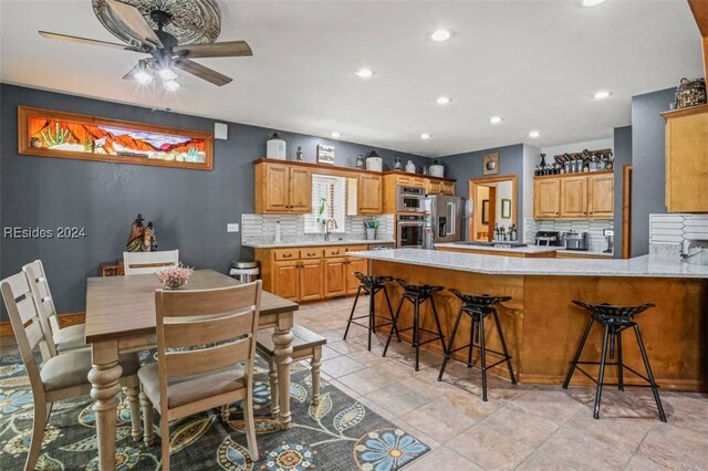 kitchen featuring tasteful backsplash, a breakfast bar, stainless steel appliances, and kitchen peninsula