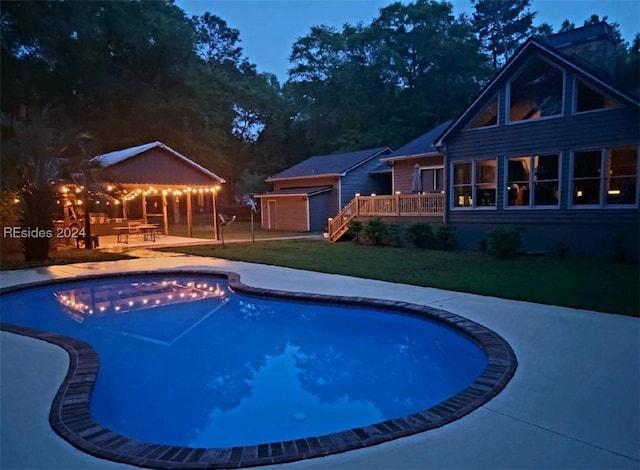 view of swimming pool featuring an outbuilding, a yard, a wooden deck, and a patio