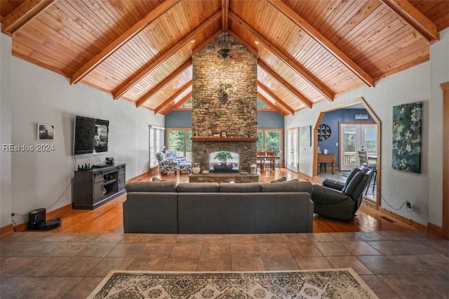 living room featuring beam ceiling, a stone fireplace, wooden ceiling, and high vaulted ceiling