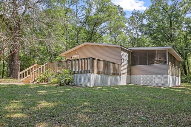 view of home's exterior featuring a wooden deck, a sunroom, and a lawn