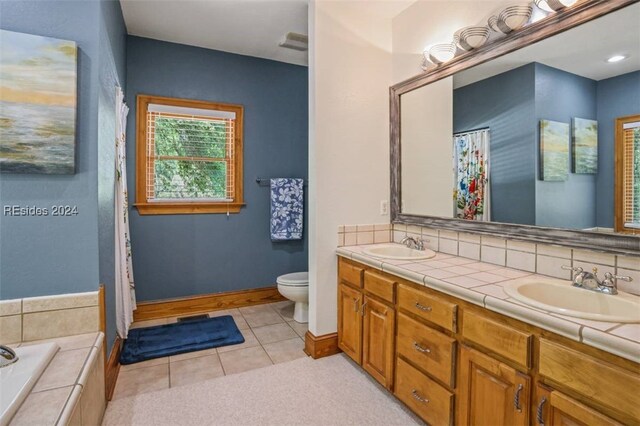 bathroom with decorative backsplash, tile patterned flooring, vanity, a relaxing tiled tub, and toilet