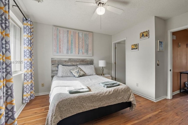 bedroom featuring hardwood / wood-style flooring, a textured ceiling, ceiling fan, and multiple windows