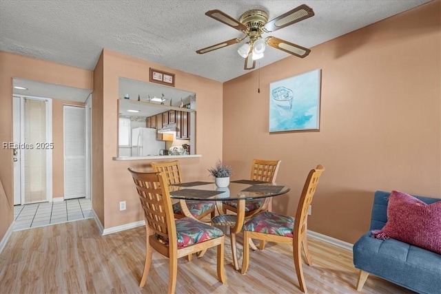 dining area featuring ceiling fan, light hardwood / wood-style flooring, and a textured ceiling