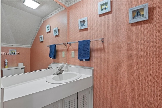 bathroom with lofted ceiling, ornamental molding, toilet, and vanity