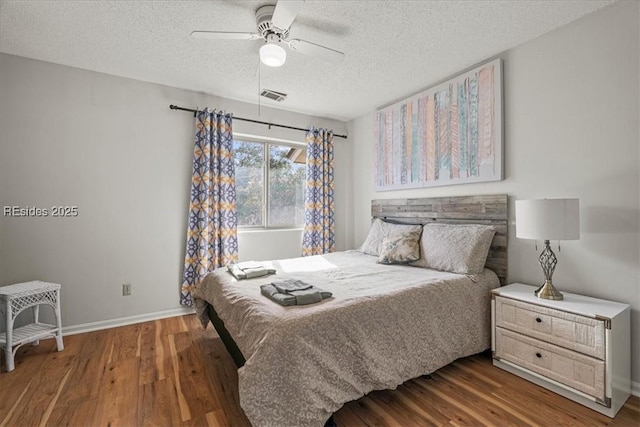 bedroom featuring dark hardwood / wood-style flooring, a textured ceiling, and ceiling fan