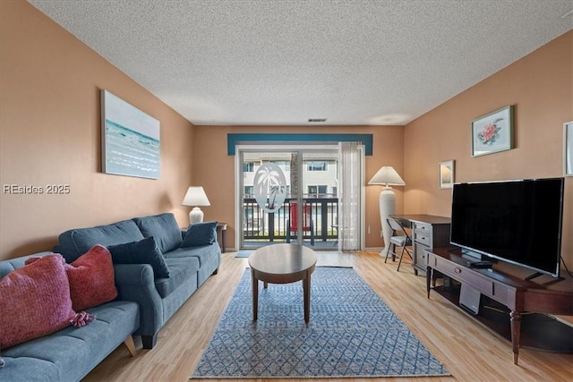 living room with a textured ceiling and light wood-type flooring