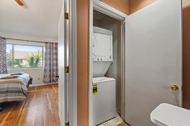 clothes washing area featuring stacked washer / dryer and light wood-type flooring