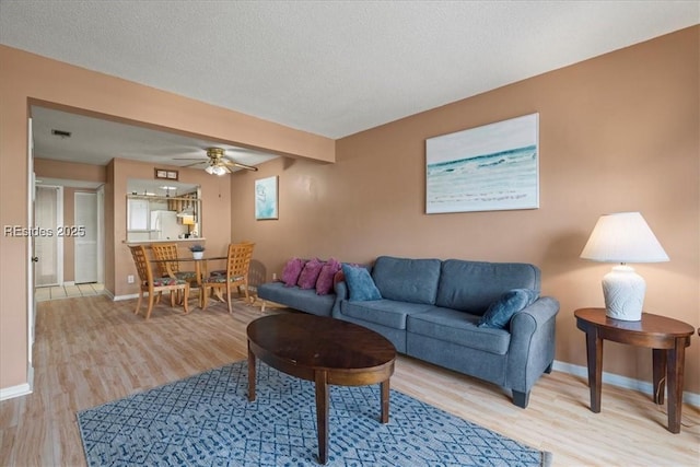 living room with ceiling fan, light hardwood / wood-style flooring, and a textured ceiling