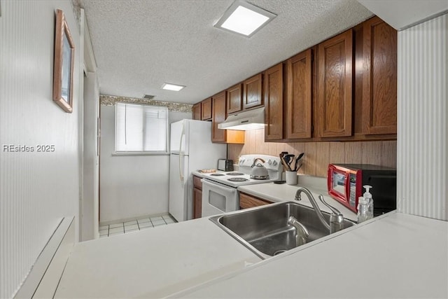 kitchen featuring sink, a textured ceiling, white appliances, and kitchen peninsula