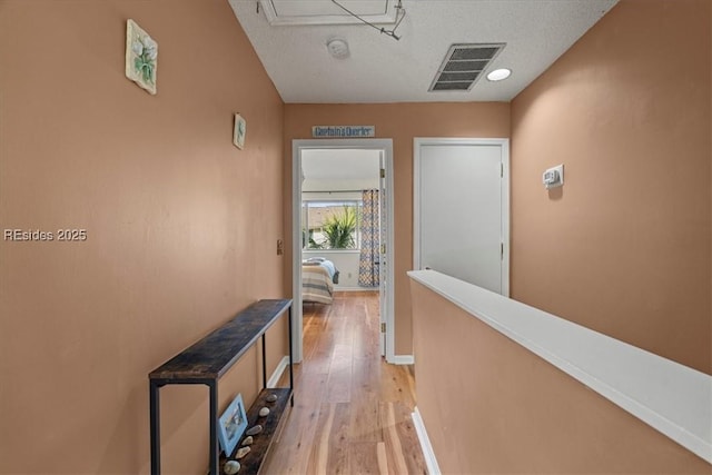 hallway with a textured ceiling and light wood-type flooring