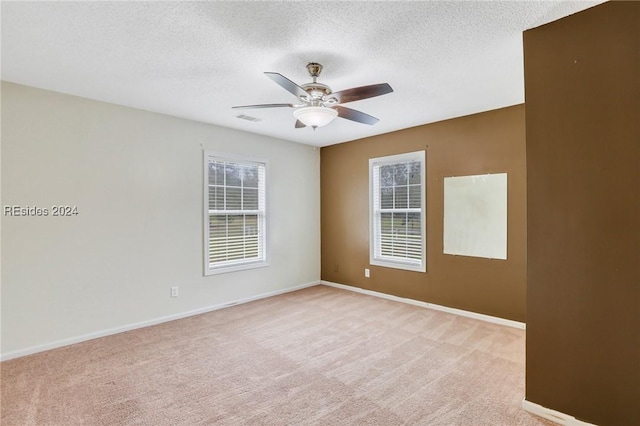 unfurnished room with ceiling fan, light carpet, and a textured ceiling