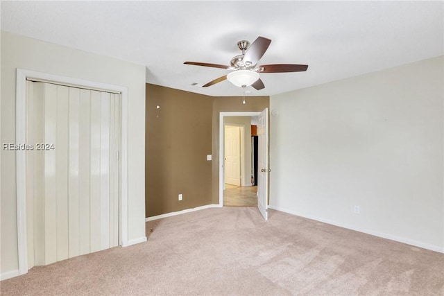 unfurnished bedroom with light colored carpet, a closet, and ceiling fan