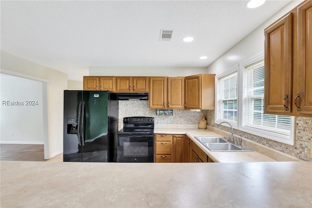 kitchen with sink, backsplash, black appliances, and a textured ceiling