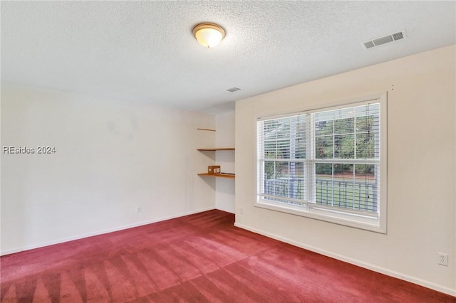 carpeted empty room featuring a textured ceiling