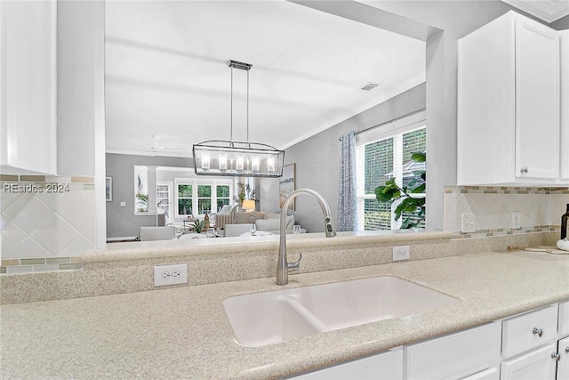 kitchen with pendant lighting, crown molding, sink, and white cabinets