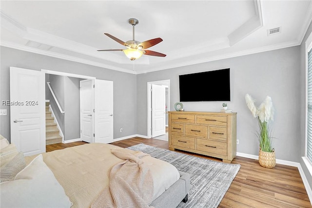 bedroom with crown molding, ceiling fan, a raised ceiling, and hardwood / wood-style floors