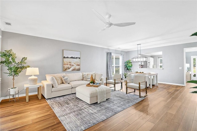 living room with ceiling fan with notable chandelier and light hardwood / wood-style flooring