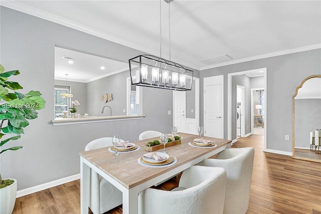 dining area featuring an inviting chandelier, crown molding, and light hardwood / wood-style flooring