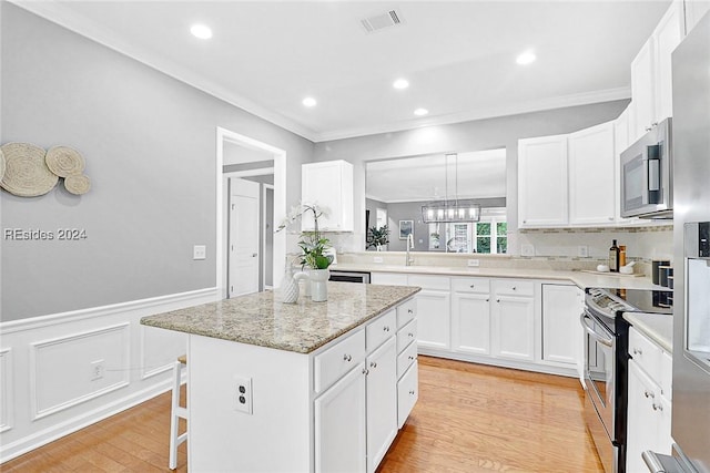 kitchen with crown molding, stainless steel appliances, a kitchen island, and white cabinets