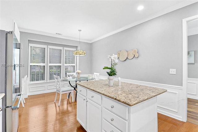 kitchen featuring white cabinetry, crown molding, a center island, hanging light fixtures, and stainless steel fridge